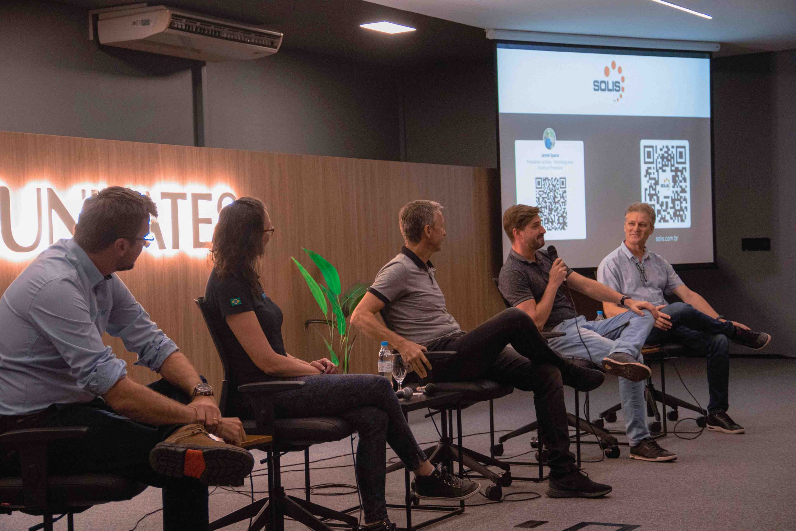 Imagem mostra diretor e painelistas em auditório da Univates, com estudantes da graduação em tecnologia na plateia